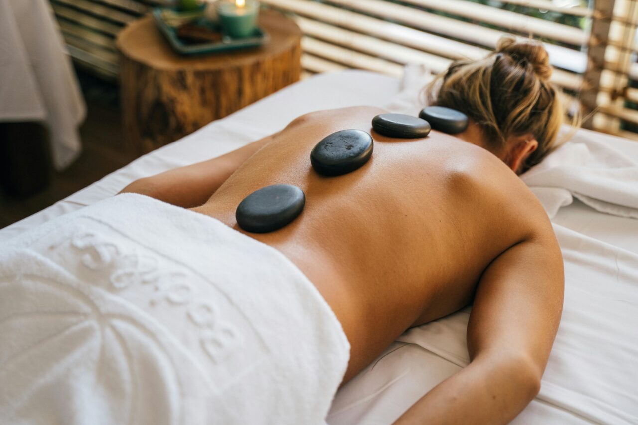 Bei der Hot Stone Massage wird die Durchblutung durch das Auflegen warmer Steine gefördert.